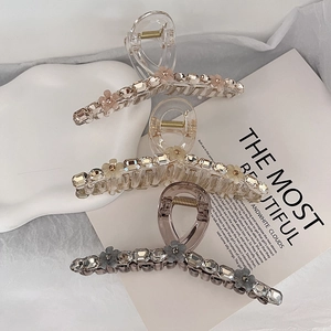 Detailed close-up of three K9 crystal hair claws with rhinestone flower accents in soft light