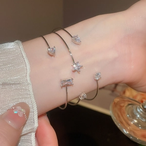 Detailed view of silver open wrap bracelet with sparkling heart and star zircon stones