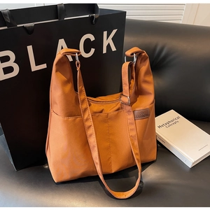 Detail of orange nylon tote bag with adjustable strap and functional front pocket