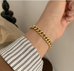 Bracelet gourmette épaisse dorée à l'or fin style français sur poignet de femme
