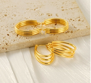 Detail of gold multi-layered circular stainless steel earrings on a soft cloth