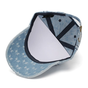 Detail view of denim baseball cap interior with butterfly print and adjustable strap