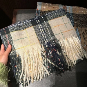 Close-up of thick checkered mohair scarf featuring soft woven texture and tassel fringes