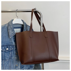 Détail d'un grand sac cabas marron foncé avec coutures verticales sur cuir synthétique