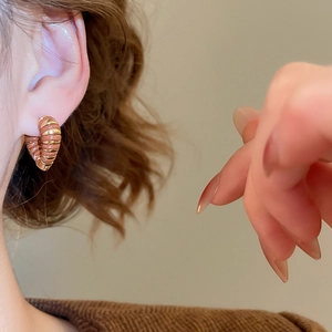Détail des boucles d'oreilles créoles torsadées en or 18 carats avec émail brun