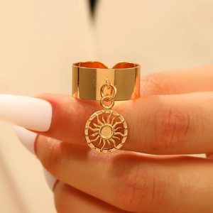 Vista macro di un anello d'oro aperto con un ciondolo a sole vintage su una fascia larga