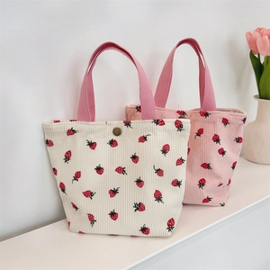 Détail de sacs cabas en velours côtelé avec imprimé fraise, poignées et fermoir magnétique