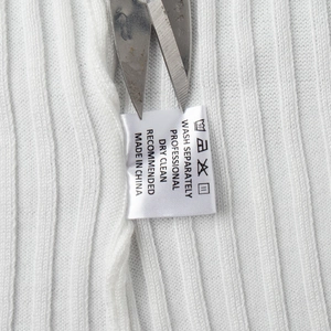 Detail view of the wash care tag and white ribbed knit fabric on a slim summer dress