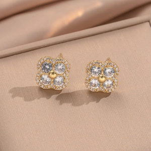 Elegant gold four-leaf clover stud earrings with sparkling cubic zirconia on silk