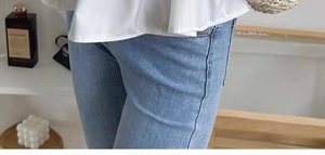 Close-up of light blue denim jeans waist and upper leg detail in a minimalist setting