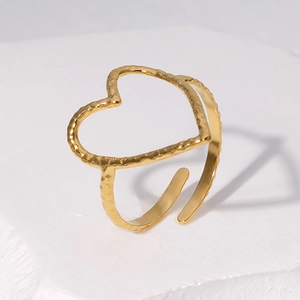 Golden heart-shaped open ring with hammered texture on a white stone base