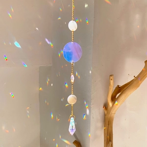 Hanging suncatcher with crystal prisms creating rainbow reflections on a white wall