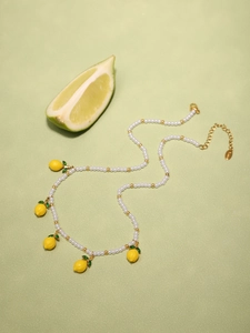 Dettaglio della collana di perle con ciondoli a limone in resina e perle bianche lucide