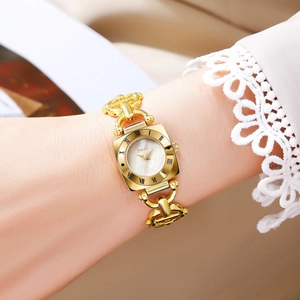 Close-up of a vintage gold bracelet watch with a square pearl dial on a woman's wrist