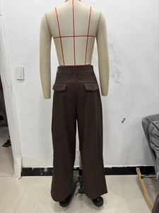 Rear view of brown wide-leg trousers showing pleated waist and decorative back pockets