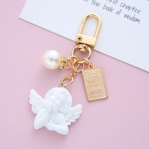 Close-up of vintage baroque angel keychain with white pearl and gold engraved tag detail
