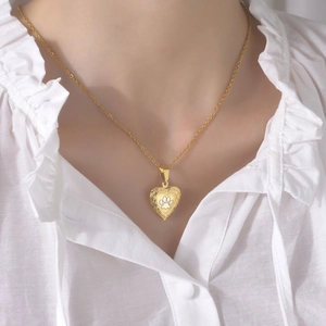 Detail of heart locket pendant with paw print engraving on gold steel chain