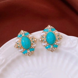 Vue macro des boucles d'oreilles ovales dorées avec émail turquoise et strass blancs