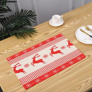 Detailed view of a Christmas placemat with red reindeer and snowflake patterns on a wooden table.