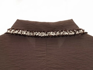 Close-up of lapel collar with tricolor braided fringe trim and woven fabric texture