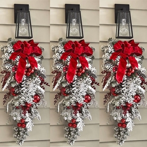 Flocked Christmas teardrop swag with red velvet bow, berries and pine cones on a wall