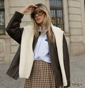 Dettaglio della gonna a pieghe scozzese marrone stile college con camicia a righe blu