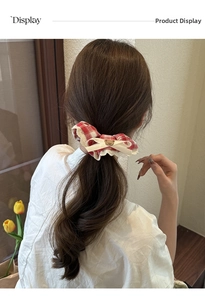 Detailed view of red plaid scrunchie with lace edge and cute bear charm on hair