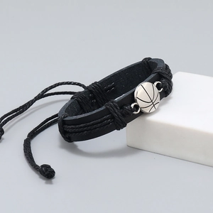 Handwoven black leather bracelet with silver basketball charm on minimalist white pedestal