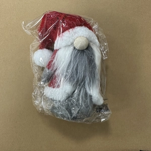 Close-up of red and grey Christmas gnome plush doll in protective plastic packaging