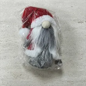 Close-up of red and grey Christmas gnome plush doll in protective plastic packaging