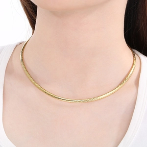Close-up of a minimalist gold geometric choker necklace on model with metallic texture
