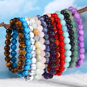 Multiple 8mm natural stone beaded bracelets hanging outdoors against a blue sky background