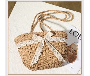 Detail of straw tote bag with white lace bow and fine woven texture on cotton background