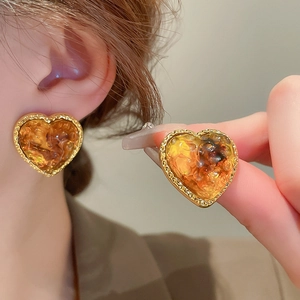 Detail of vintage heart earrings with amber resin and twisted gold metal borders