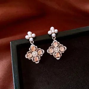 Elegant gold flower drop earrings with champagne zircons and pearls on silk background