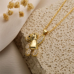 Macro di una collana con ciondolo a orso dorato e zirconi su pietra e seta elegante