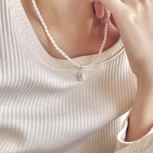 Detail of freshwater pearl necklace with silver bear pendant on a white sweater
