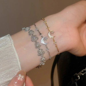 Detail von 18k vergoldeten Mondanhängern und Zirkon-Armbändern an elegantem Handgelenk