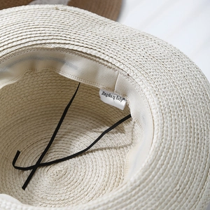 Detail of raffia straw hat interior with sweatband, elastic chin strap and brand label