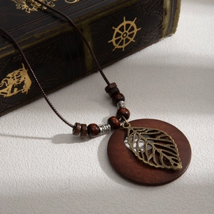 Vintage bohemian necklace with brown wooden circle pendant and bronze metal leaf charm