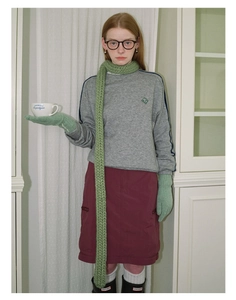 Close-up detail of knitted green scarf and matching gloves for winter fashion styling