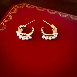 Elegant gold C-shaped double-layer earrings with pearls on a red luxury gift box