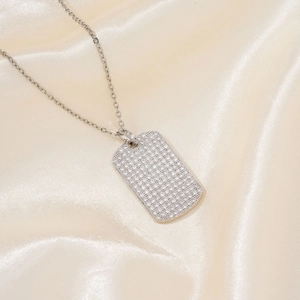 Close-up of a silver rectangular pendant necklace with sparkling pavé crystals on silk