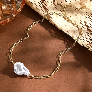 Close-up of Baroque irregular pearl necklace with gold chain on warm textured background