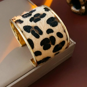 Detailed view of leopard print texture on a wide golden metal cuff bracelet