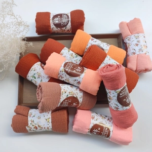 Detail of multi-color pleated cotton scarves with Fashion COTTON labels on a wooden tray