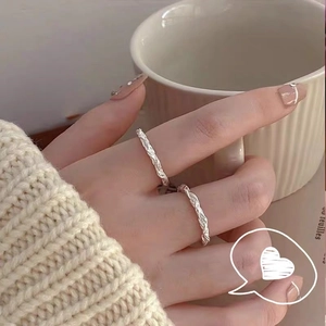 Minimalist silver twist ring set featuring textured braided metal bands on models fingers