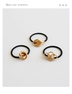 Close-up of minimalist gold metal knot hair ties on black elastic bands, set of 3