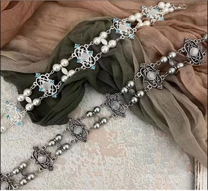 Close-up of vintage pearl bracelets with blue and grey gemstones on wrinkled fabric