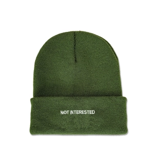 Detailed view of white NOT INTERESTED embroidery on dark green knit beanie hat